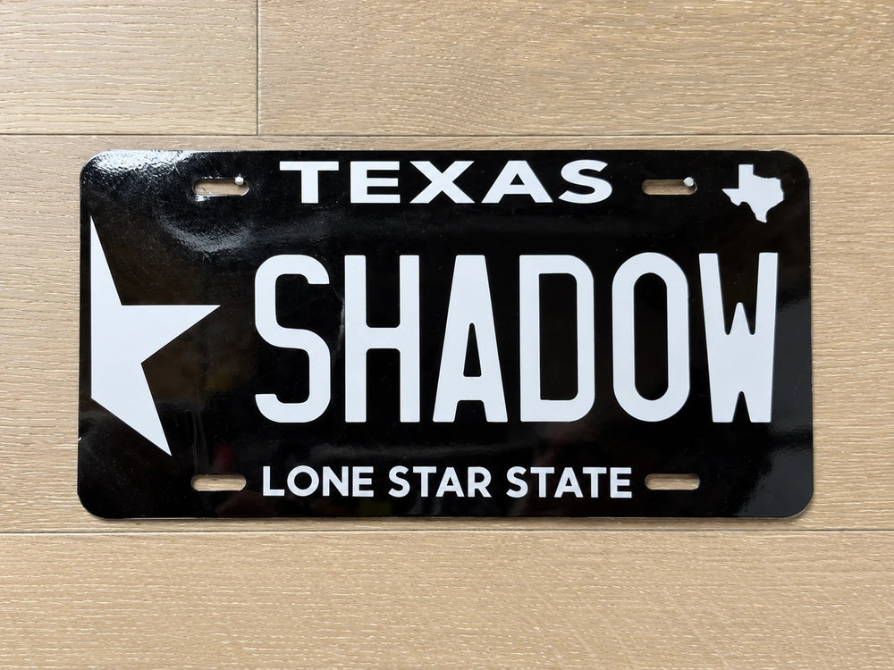 Close-up of the black SHADOW plate with white Texas artwork and Lone Star State tagline.