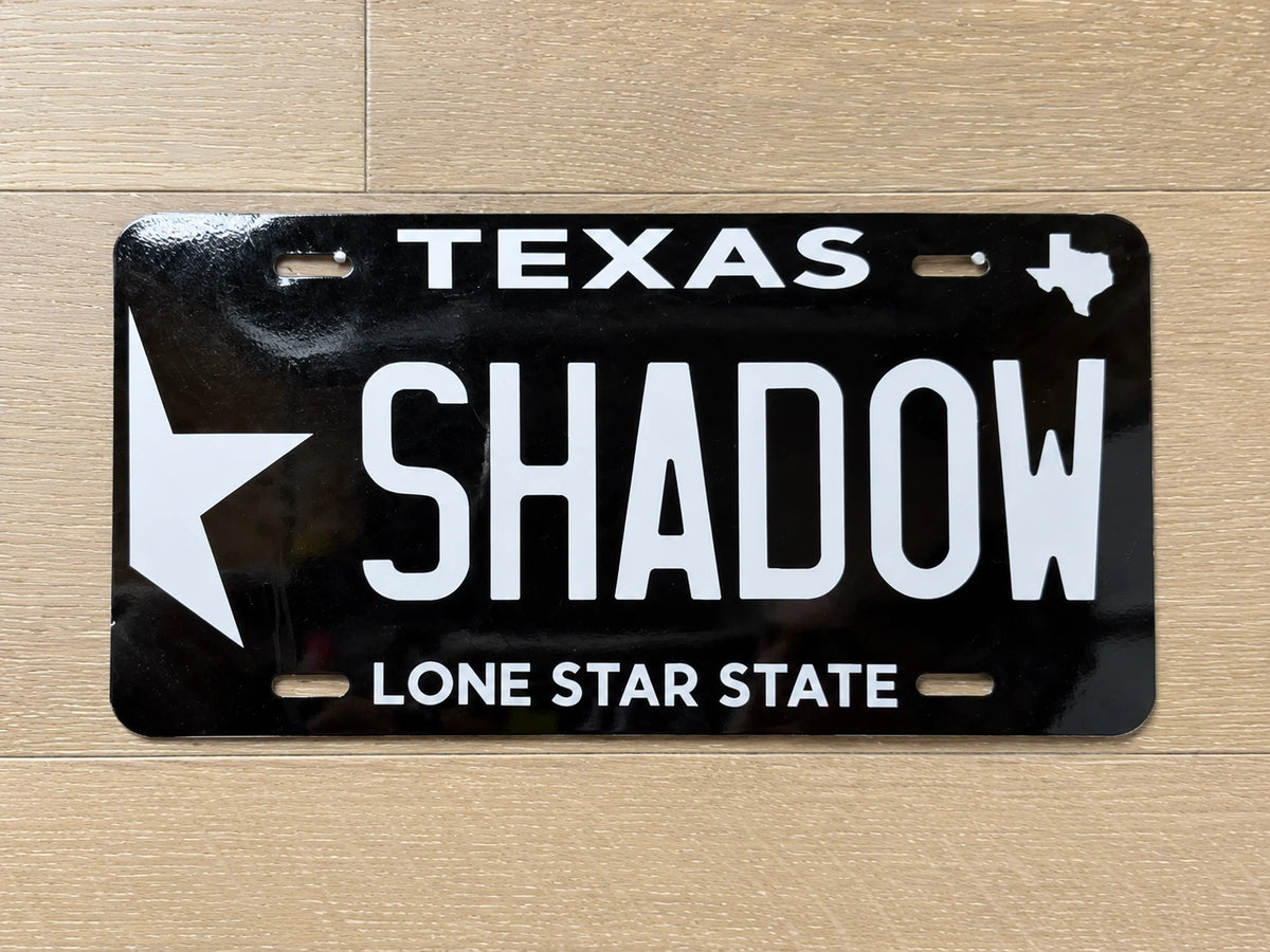 Close-up of the black SHADOW plate with white Texas artwork and Lone Star State tagline.